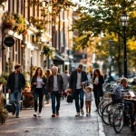 Drukke Amsterdam gracht met mensen wandelen, fietsen en terrassen langs historische Nederlandse gebouwen