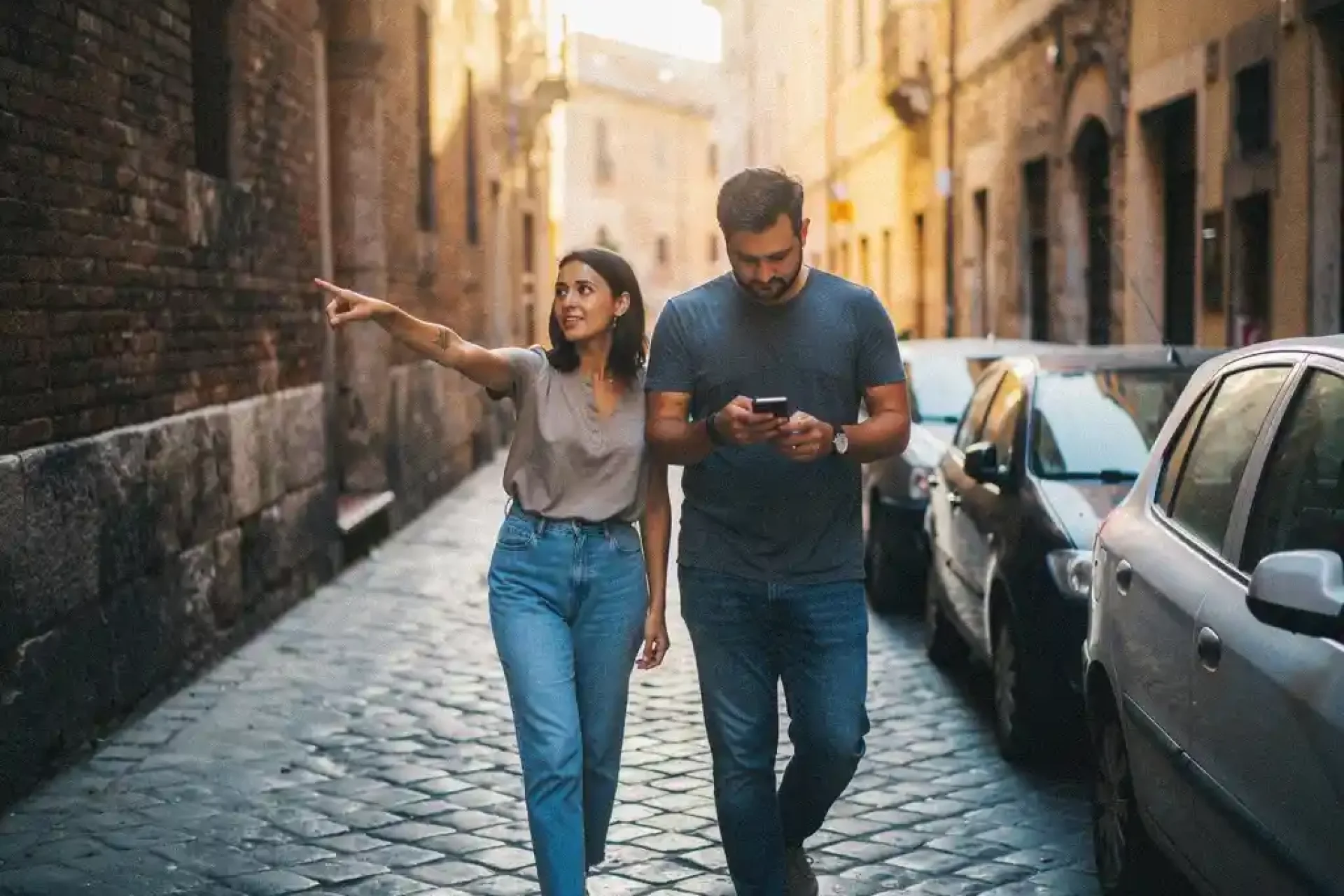 Twee mensen lopen samen door smalle kasseienstraat in historisch Europees stadscentrum tijdens gouden uur