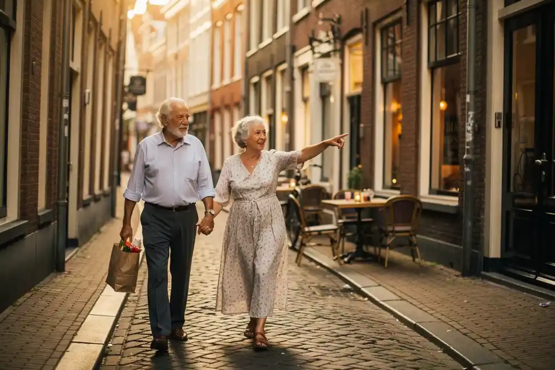 Bejaард stel wandelt hand in hand door smalle kasseienstraat in historisch Nederlands stadscentrum bij gouden middaglicht.