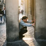 Persoon meet kleine parkeerplaats tussen betonnen pilaren in smalle Europese straat met kinderkopjes