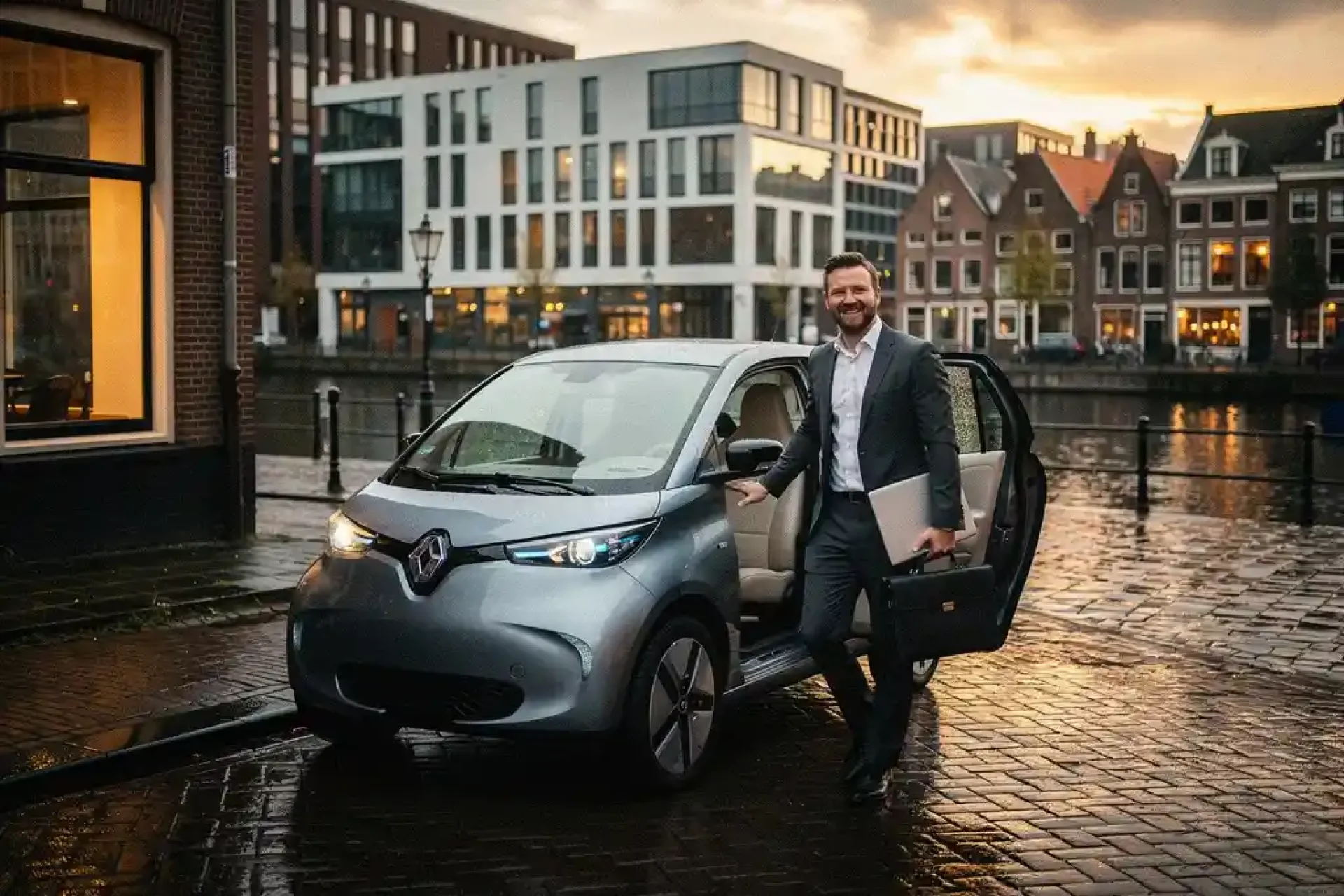 Elektrische stadsauto geparkeerd langs Utrechtse gracht, professional stapt uit met laptoptas op natte klinkerstraat.
