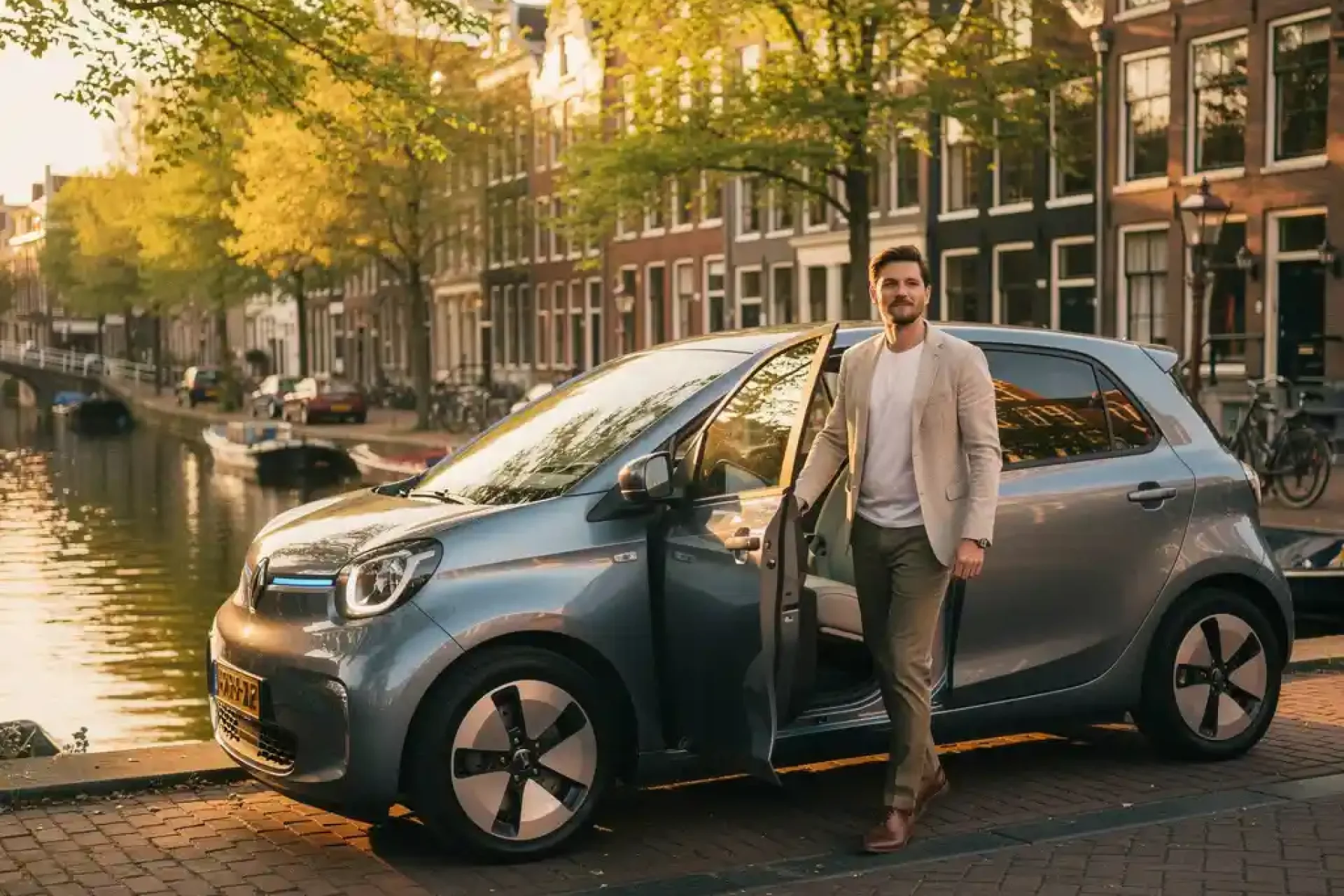 Jonge professional stapt uit elektrische microcar langs Amsterdamse gracht, omgeven door kanaalshuizen en lindebomen in middagzon.