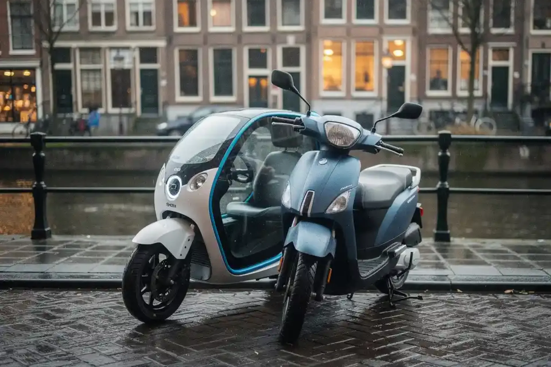 Compacte elektrische stadsauto en scooter naast elkaar op natte Amsterdamse klinkerstraat langs een gracht, met typische bakstenen gevels op de achtergrond.