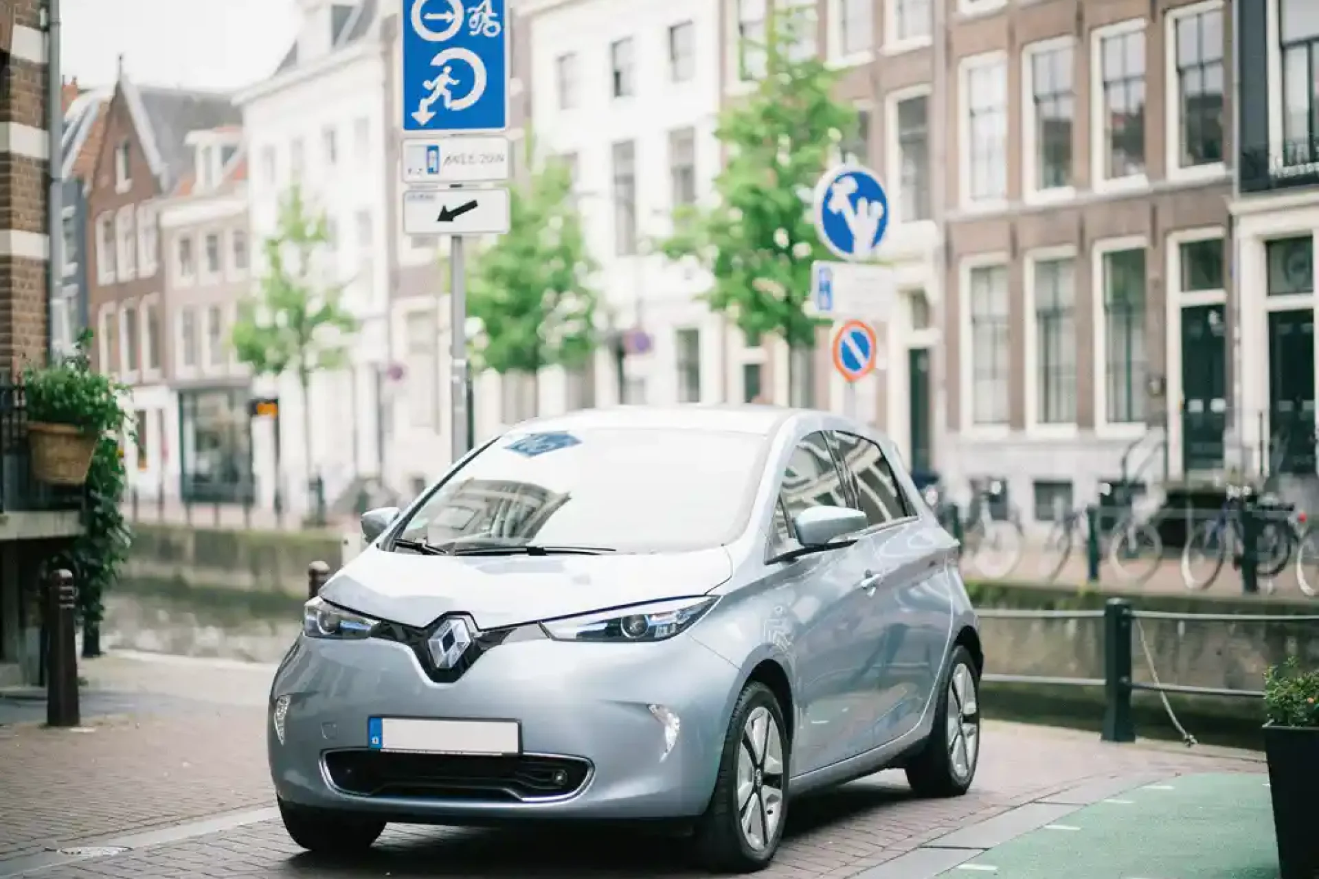 Compacte elektrische stadsauto bij ingang van een zero-emissiezone in Utrecht, met kanaalarchitectuur en bakstenen gevels op smalle straat.