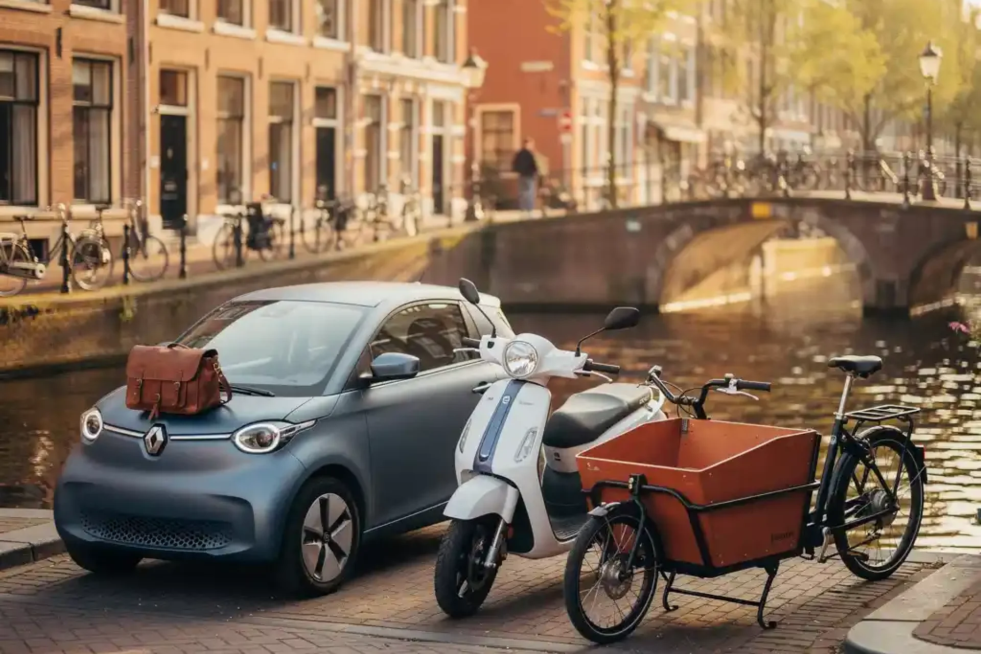 Elektrische stadsauto, scooter en bakfiets naast elkaar op een zonnige Amsterdamse gracht met leren tas op de motorkap.