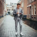 Jonge professional bekijkt aantekeningen buiten een modern kantoorgebouw in Utrecht, smal grachtstraatje op de achtergrond.